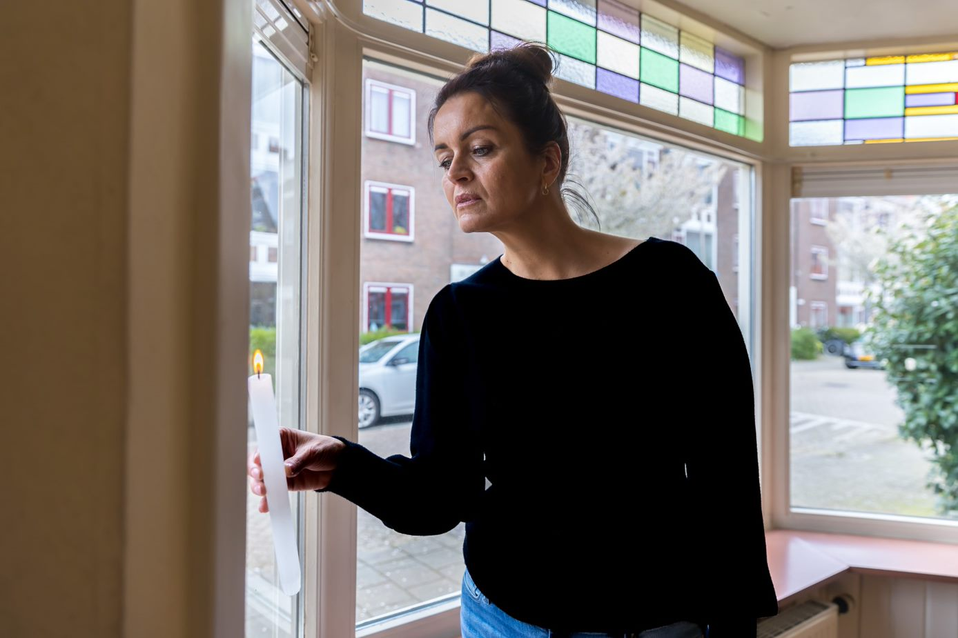 Vrouw controleert met een kaars of er tocht uit de muur komt.