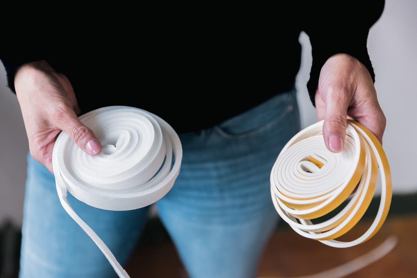 Vrouw houdt twee rollen tochtband in haar handen.